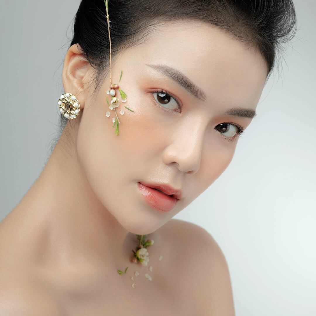 Asian woman intense eyes hair up. Best anti-aging face oil.