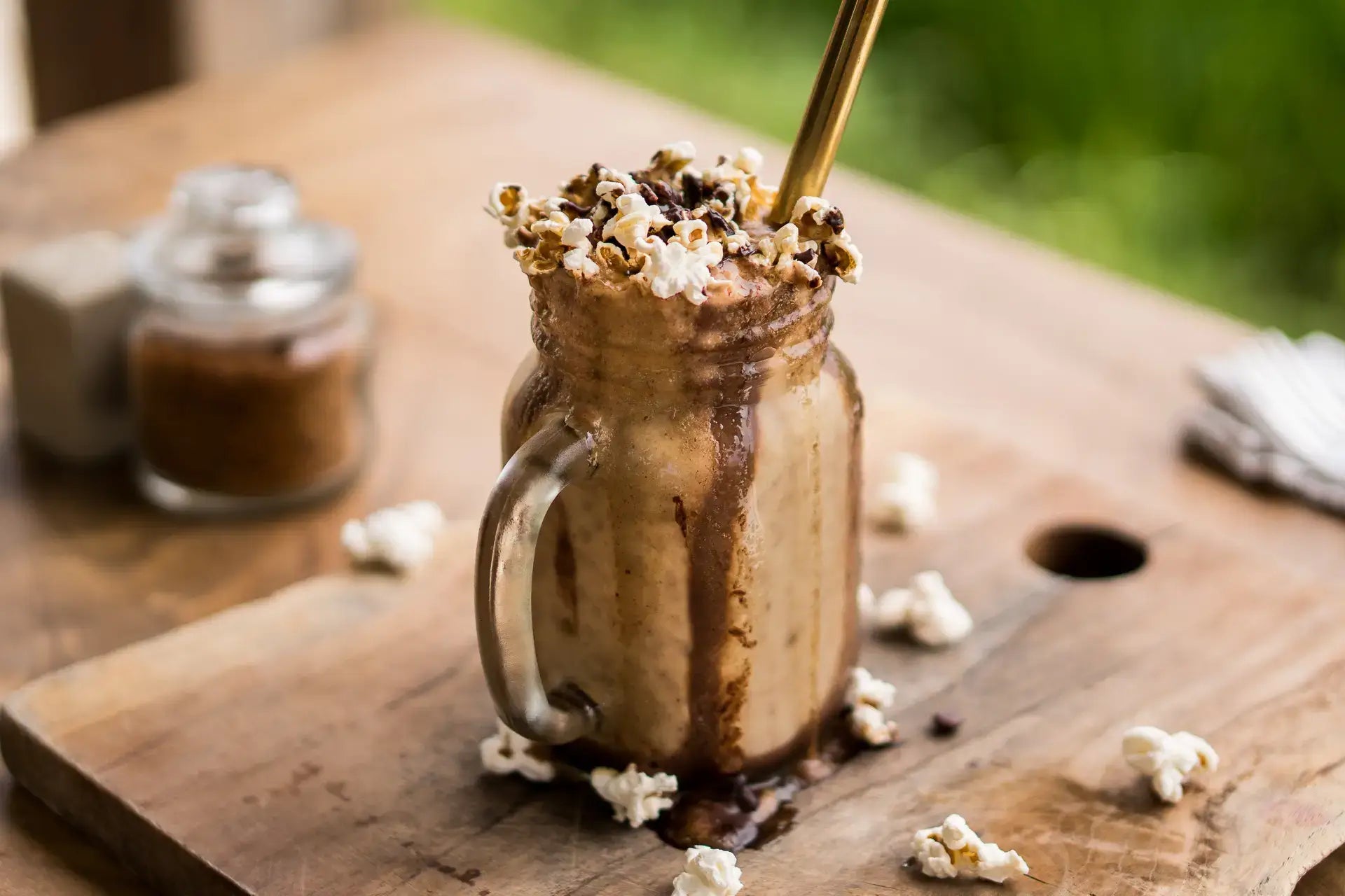 Vegan chocolate Smoothie with popcorn on top sitting on wood table. Recipe inside Bali Vegan book