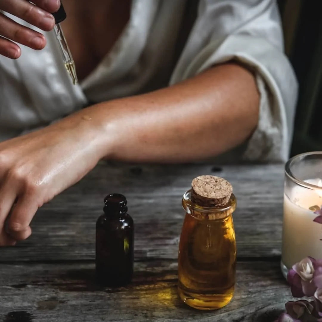 The best face oil for oily skin, applying oil dropper to woman's arm on old wood table